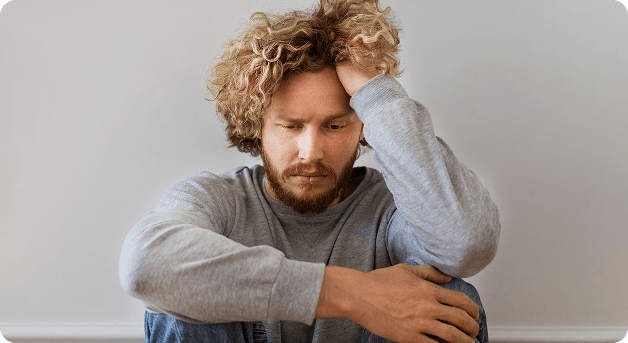Thoughtful person representing our team - curly-haired man in gray sweater
